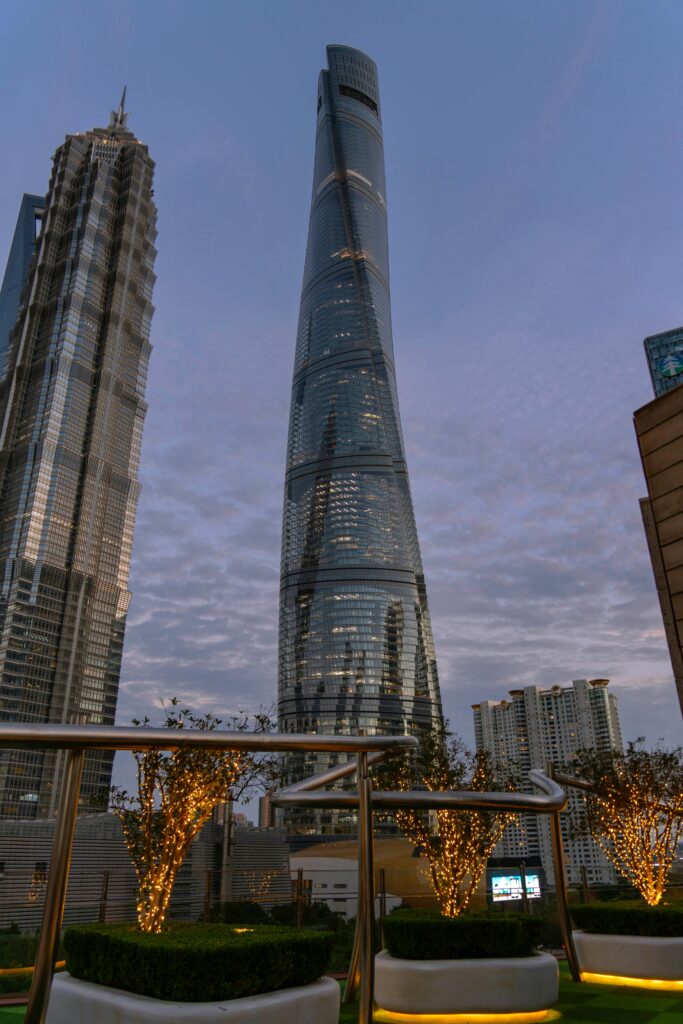 Stunning view of Shanghai Tower at twilight surrounded by lit trees and nearby skyscrapers.